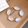 Close-up of French vintage gold bracelet with five oval faceted white resin stones on tray. - Gold-White