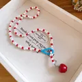 Primo piano di una collana di perle bianche e rosse con ciondolo a mela per ragazze - Collana-Bianco-Rosso