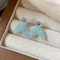 Close-up detail of light blue beaded fishtail earrings inside a cream jewelry box - Fish Tail Style (HE31327) / Blue