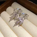 Macro shot of silver-plated clip-on earrings featuring sparkly zircon flower and leaf motifs - Clip-On Earrings / Silver