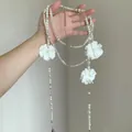 Dettaglio della collana lunga di perle multistrato con eleganti fiori di camelia. - Bianco