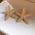 Detail view of golden starfish earrings with textured surface and minimalist fashion design. - Starfish Style (HE32782) / Gold