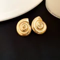 Close-up view of vintage gold conch shell stud earrings with spiral metallic texture - Earrings / Gold