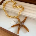 Close-up of a vintage acrylic brown starfish pendant on a gold chain necklace in a box - Starfish (HN11845) / Brown