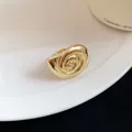 Macro view of a vintage style gold conch shell ring resting on a white ceramic plate - Ring / Gold