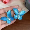 Detailed close-up of blue enamel butterfly stud earrings with sparkling zircon accents - Butterfly Style (Alloy) / Silver Needle / Gold/Blue