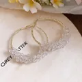 Detail showing elegant gold-toned hoop earrings with clear faceted crystal beads. - Gold-White