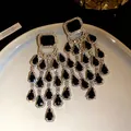 Detailed macro view of elegant black teardrop tassel earrings with sparkling rhinestone studs - Silver Earring Post Style / Black