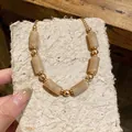 Detail of vintage Maillard acrylic necklace featuring marbled beige beads and gold accents - Beige