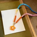 Detailed macro view of a colorful dopamine glass beaded necklace with flower pendant - Orange Multicolor Necklace