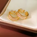 Close-up of elegant gold-plated hoop ear clips with sparkling crystal inlay in gift box - Gold
