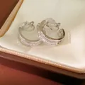 Detail shot of silver gold-plated hoop clip-on earrings with pavé stones in a box - Silver