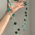 Vista dettagliata di una lunga collana di perline con dischi di conchiglia turchese - Collana Lunga (Catena per Maglione) / Verde
