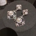 Dettaglio di orecchini vintage in argento con aureole di zirconi e perle centrali - Argento