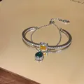 Detailed shot of a silver double-layer bracelet with emerald and yellow gemstones - Silver