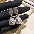 Vista dettagliata di orecchini pendenti con perle barocche vintage e motivi floreali in argento. - Argento & Bianco
