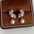 Dettaglio macro di eleganti orecchini in argento con perle e zirconi in scatola marrone. - Argento + Rosa