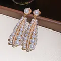 Eleganti orecchini vintage a goccia traforati con perle lucenti e zirconi brillanti. - Oro