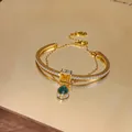 Detail view of double-layer gold bracelet with yellow zircon and emerald-green teardrop - Gold