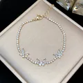Close-up detail of a sparkling gold butterfly zircon bracelet on a jewelry box. - Gold-White