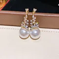 Dettaglio di eleganti orecchini a goccia con perle e zirconi dorati e aghi in argento - Oro