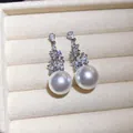 Primo piano di eleganti orecchini a pendente con perle e zirconi in un portagioie - Argento