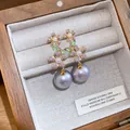 Primo piano di orecchini a fiore in argento con zirconi e pendenti di perle viola - Oro + Viola
