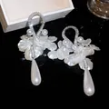 Dettaglio di eleganti orecchini con zirconi e perle a goccia bianche - Argento & Bianco
