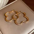 Detailed close-up of sparkling gold flower hoop earrings with micro-pave cubic zirconia - Flower Style (HE33939) / Gold
