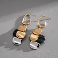Close-up of gold-plated metal dangle earrings with mixed color sequins on grey texture - Twisted Sequin Geometric Style (HE7032) / Black Gold Silver Patchwork