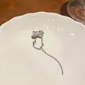 Close-up of a silver butterfly tassel ear cuff with sparkling stones on a ceramic plate - Single Piece (Real Gold Plated) / Silver