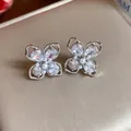 Close-up of four-leaf flower earrings with zircons and pearls on gold display box - Silver