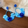 Detailed macro view of blue raffia hoop earrings decorated with fabric flower petals - Blue