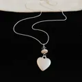 Macro view showing close-up detail of silver heart pendant necklace with cream bead accents - Letter Heart Pendant / Silver