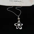 Detailed view of silver flower pendant necklace with heart center on black velvet - Hollow Flower Pendant / Silver