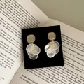 Close-up of elegant gold stud earrings with layered white shell-like circular pendants - Cat's Eye Tassel Style (HE33304-1-) / White