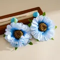 Detailaufnahme von Boho-Ohrringen aus blauem Stoff und Bast auf einem Holzständer - Blau