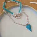 Macro view of a multi-layer pearl necklace featuring a turquoise heart pendant and flowers - Necklace / Blue