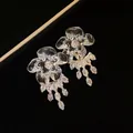 Dettaglio di eleganti orecchini a fiore in resina con nappe in zircone luccicanti. - Stile Nappa a Catena in Zirconia / Argento