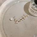 Close-up of elegant French retro asymmetric pearl earrings with zircon stones - Asymmetrical Style / Gold