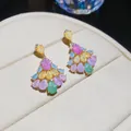 Gros plan de boucles d'oreilles en zircon coloré en forme d'éventail sur boîte à bijoux - Coloré