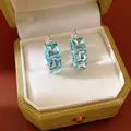 Dettaglio di orecchini a cerchio con zircone blu chiaro quadrato in scatola di velluto. - Orecchini a Bottone Quadrati (HE34060) / Blu