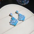 Gros plan d'élégantes boucles d'oreilles en zircon bleu en forme d'éventail dans un écrin - Bleu