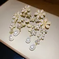 Close-up of elegant floral earrings with pearls and crystals on a creamy luxury background - Vintage Pearl Flower Style (HE33370) / Gold