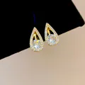 Detailed macro view of 18k gold-plated teardrop clip earrings with clear sparkling zirconia stones. - Clip-On Earrings / Gold