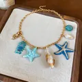 Gedetailleerd overzicht van strandketting met zeester- en schelphangers op dienblad - Oceaan Thema (HN11780) / Goud-Blauw