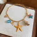 Gedetailleerde weergave van de strandketting met bedeltjes van zeesterren en schelpen. - Oceaan Thema (HN11780) / Goud-Meerkleurig