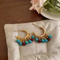 Detailed close-up of gold-plated C-shape earrings with turquoise and red resin beads - Gold-Red-Blue