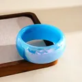 Close-up view of the vibrant blue marbled resin texture on a chunky aurora bangle bracelet - Blue