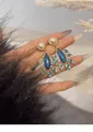 Detailed macro view of vintage palace style peacock feather earrings with blue enamel and pearls - Silver Earring Post Style / Gold with Blue